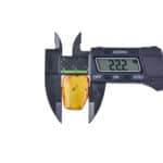 Measuring amber gemstone with digital caliper showing 22.2mm width.
