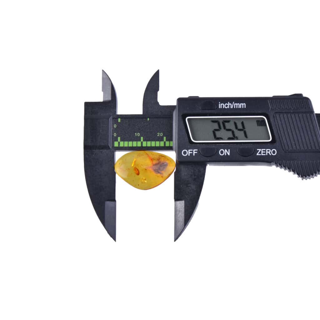 Caliper measuring a golden amber stone with inclusions, showing 25.4 mm precision.