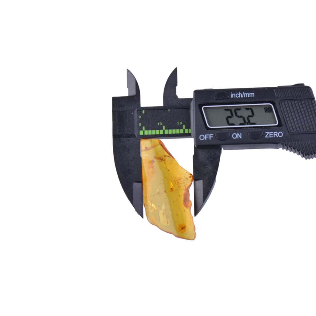 Close-up of amber being measured with a digital caliper, showcasing natural inclusions and precise size.