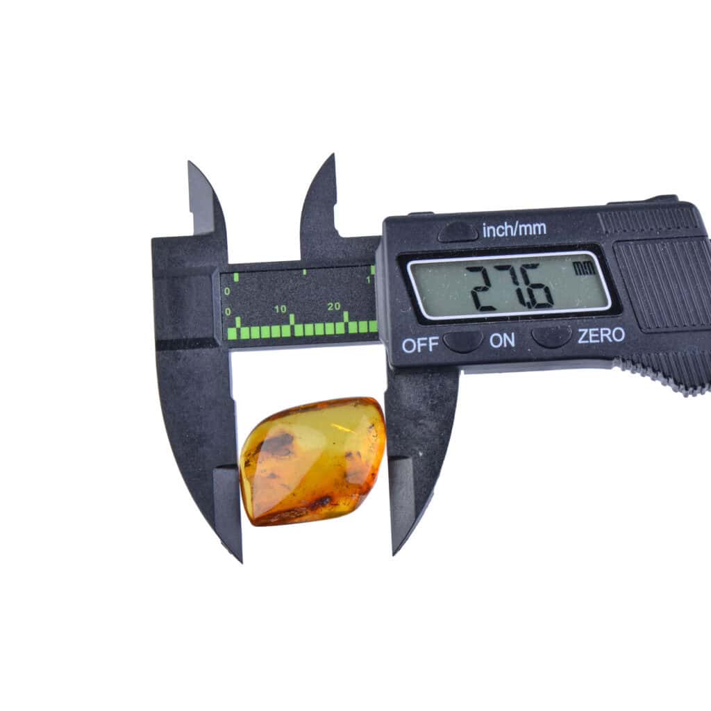 Measuring golden amber with digital caliper for jewelry, showcasing precise gemstone dimensions.