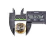 Measuring a polished, earthy-toned mineral sphere with digital caliper, 27.9 mm diameter, on white background.