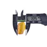 Digital caliper measuring a small amber piece with inclusions, highlighting craftsmanship and natural beauty.