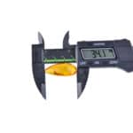 Digital caliper measuring amber, showcasing precise 34.1mm size and natural ambers warm glow.