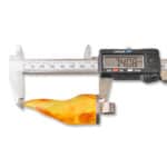 Digital caliper measuring a vibrant Baltic amber piece, size 74.08 mm, showcasing natural beauty and craftsmanship.