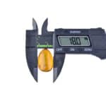 Digital caliper measuring amber with natural inclusions, highlighting precision and craftsmanship.