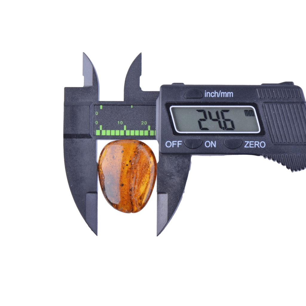 Digital caliper measuring polished amber stone with 2.46 cm precision.
