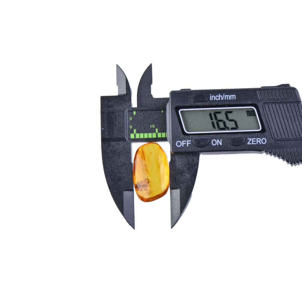 Digital caliper measuring natural amber gemstone, highlighting precision and craftsmanship in jewelry making.