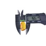 Digital caliper measuring natural amber gemstone, highlighting precision and craftsmanship in jewelry making.