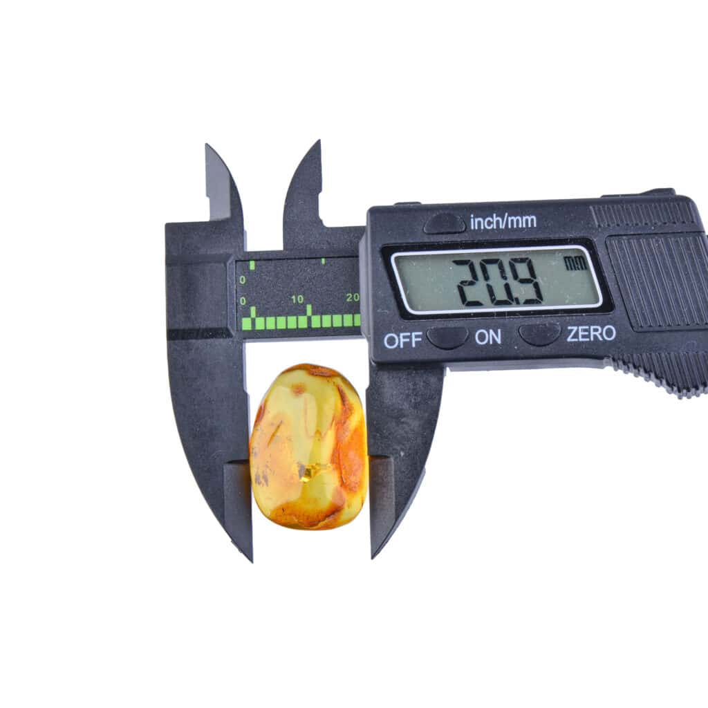 Digital caliper measures 20.9mm amber gemstone, highlighting precision and natural beauty.