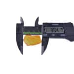 Digital caliper measuring yellowish-orange amber fragment with natural inclusions, 35.4mm size.