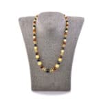 Natural Baltic amber necklace in warm cognac tones displayed on a gray bust.