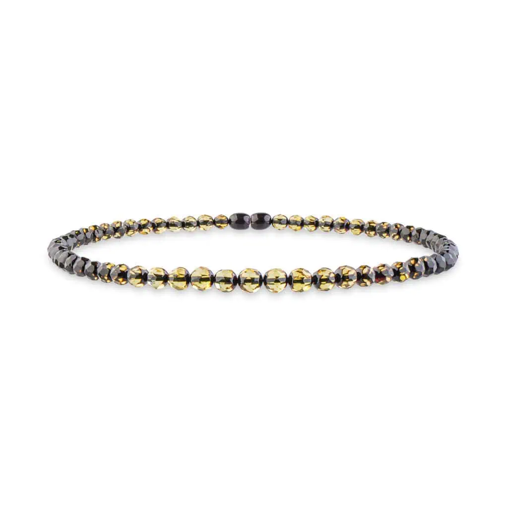 Sophisticated woman wearing black blazer and modern Baltic amber necklace with gold and black beads.
