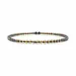 Sophisticated woman wearing black blazer and modern Baltic amber necklace with gold and black beads.