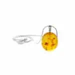 Natural Baltic amber pendant with silver chain against deep green lace dress.