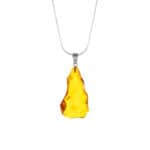 Handmade Baltic amber pendant with rustic silver chain, organic shape, warm golden glow.