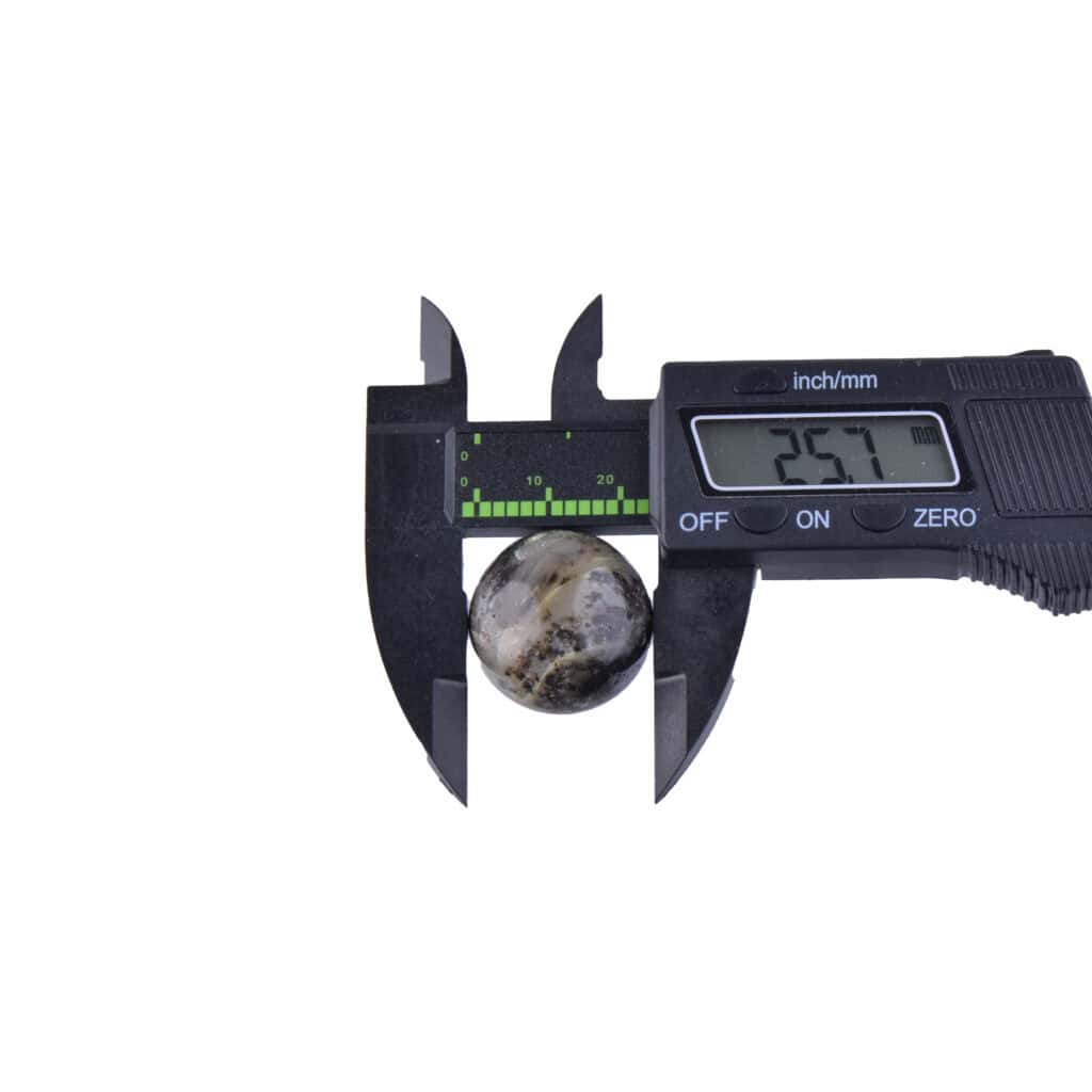 Digital caliper measuring a polished marble sphere, displaying 25.7 mm diameter measurement.