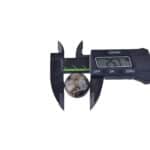 Digital caliper measuring a polished marble sphere, displaying 25.7 mm diameter measurement.