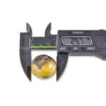 Digital caliper measuring a polished amber sphere at 29.7mm diameter.