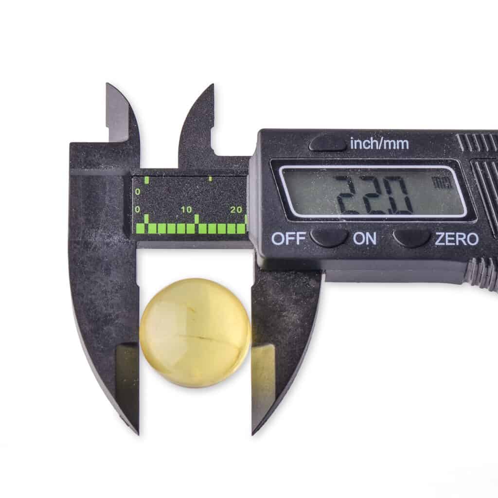 Digital caliper measuring 22mm yellow amber gemstone for jewelry and precision applications.