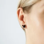 Black butterfly earring with intricate detail, elegant and reflective, highlighting delicate beauty on the ear.