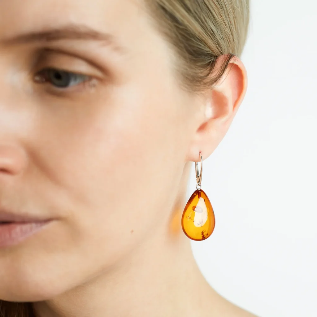 Woman in profile wearing amber teardrop earrings with silver accents, highlighting natural elegance.