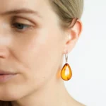 Woman in profile wearing amber teardrop earrings with silver accents, highlighting natural elegance.