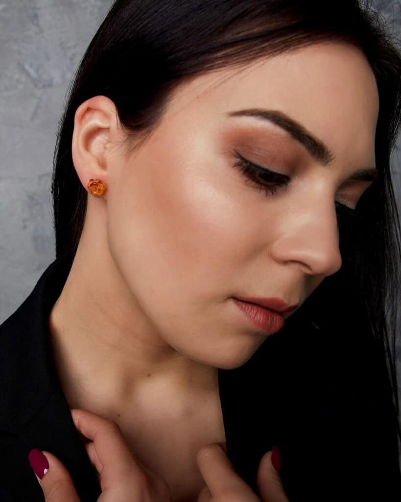 Elegant profile of a woman wearing amber earrings with a soft, natural glow.