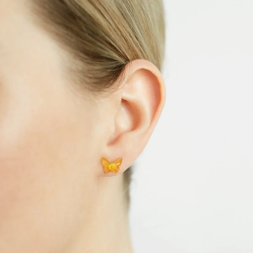 Golden butterfly earring in womans ear, highlighting elegance and craftsmanship.