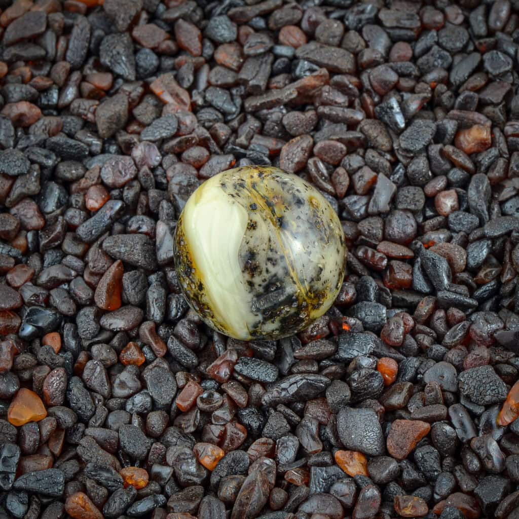 Polished black and yellow stone atop dark gravel with contrasting textures and natural shine.