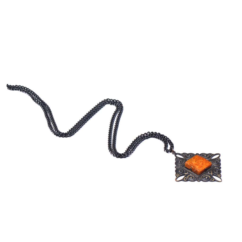 Vintage-style necklace with bold orange gemstone pendant and ornate dark metal detailing.