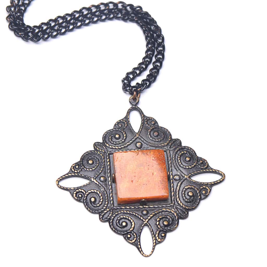 Vintage amber pendant necklace with intricate metalwork and a brass chain, elegant and timeless.