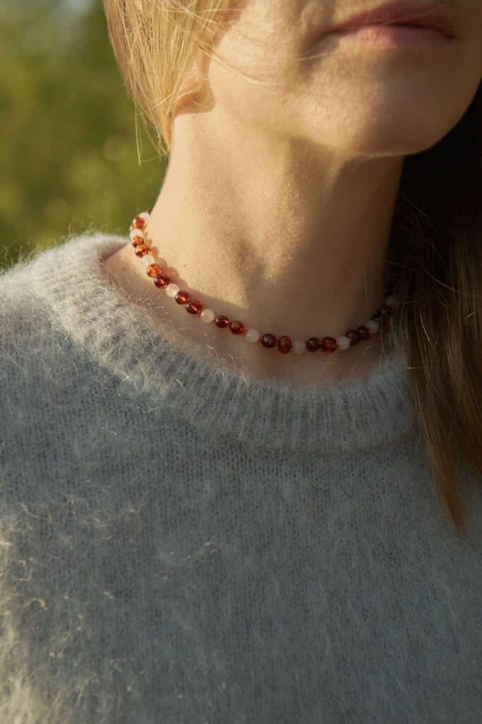 natural amber with quartz on a woman's neck surrounded by nature