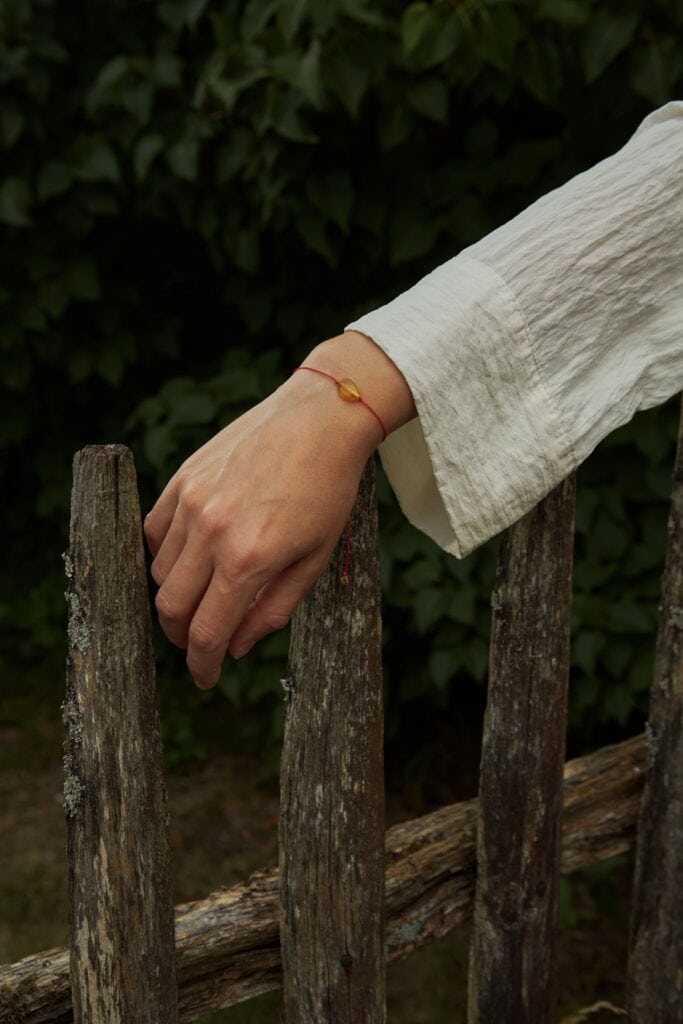 natural amber with red string on woman hand