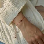 Natural amber cherry color bracelet with red string. On a woman's hand