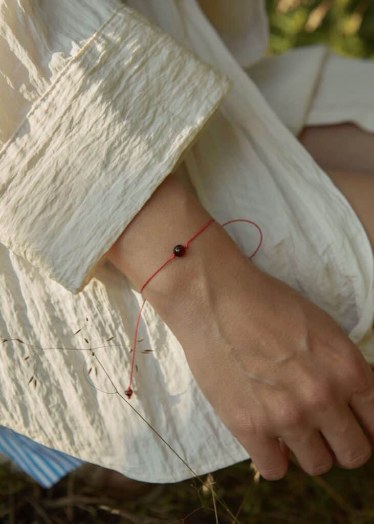 Natural amber cherry color bracelet with red string. On a woman's hand