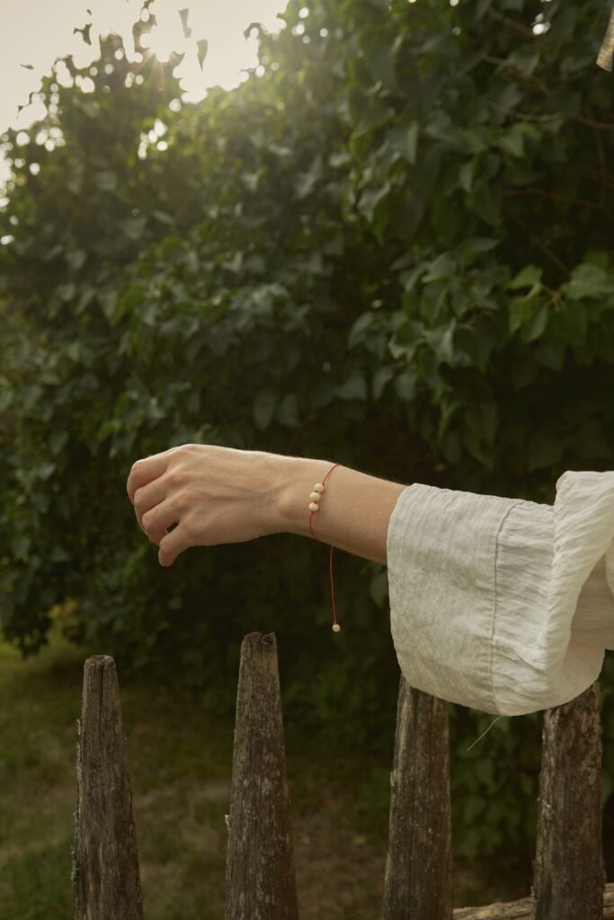 natural amber bracelet with three center beads, red string. On a woman's hand against a natural background
