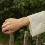 natural amber beads, three in the center with a blue string. On a woman's hand surrounded by nature