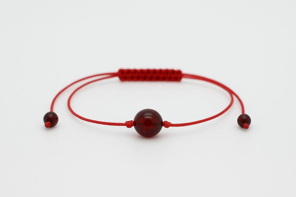 cherry colored amber with red string in the center of the bracelet