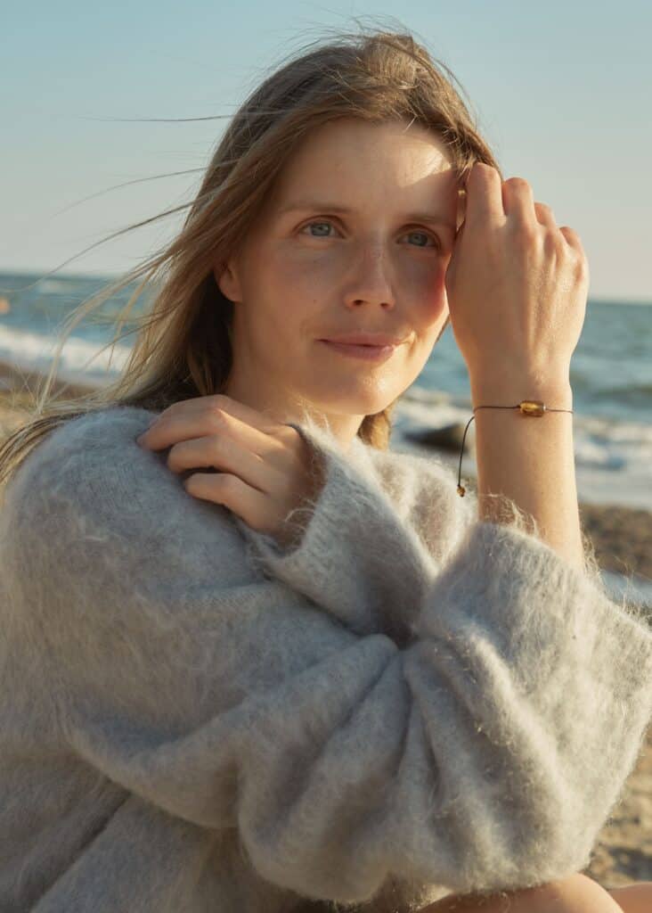 woman by the sea with a natural amber barrel-shaped bracelet